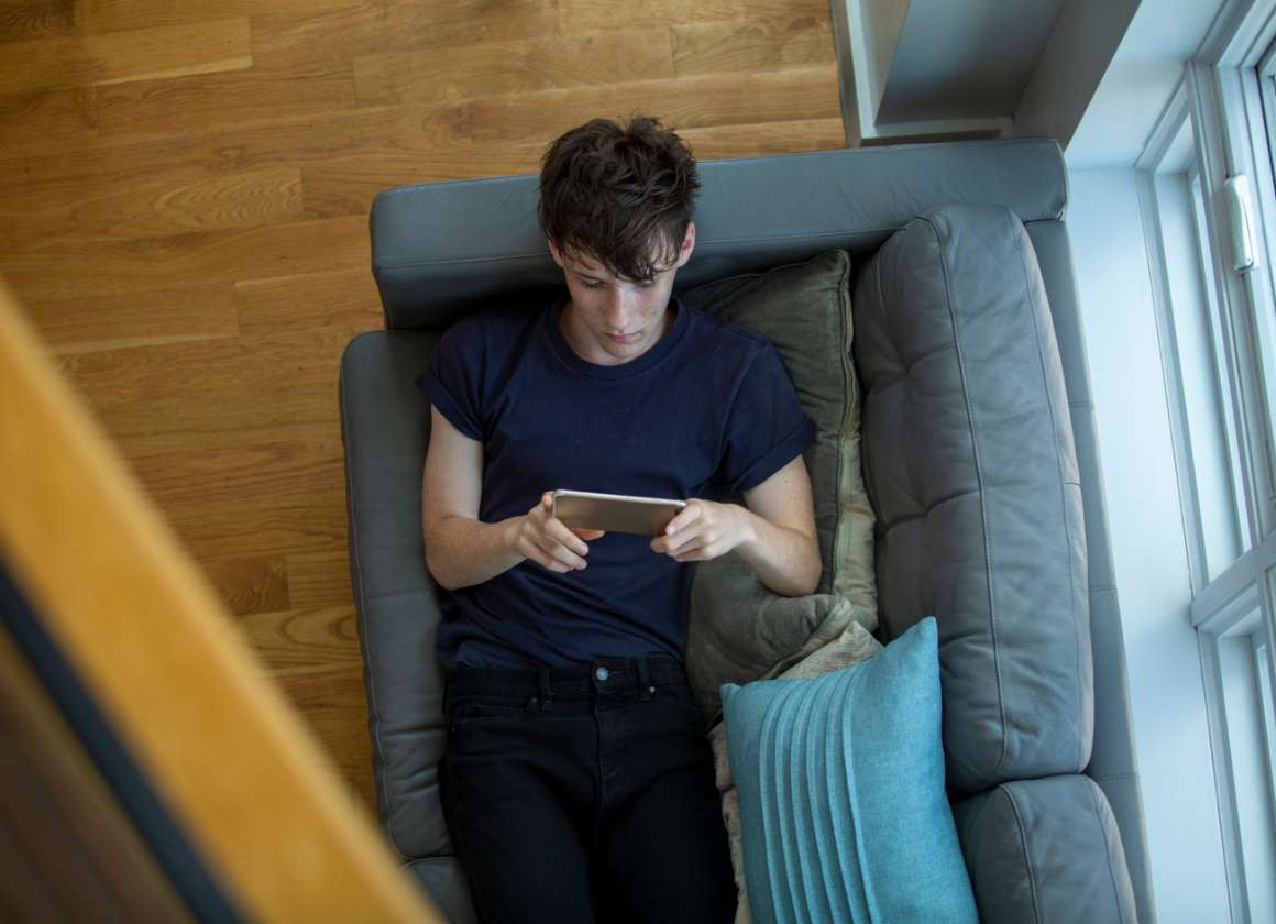 Une image sur une page Web concernant le site Web sur la santé mentale de Jeunesse, J'écoute d’une jeune personne sur un canapé regardant un téléphone