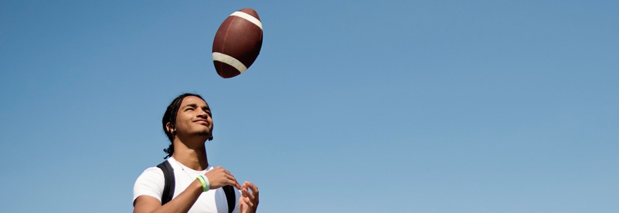 Une jeune personne lance un ballon de football en l'air