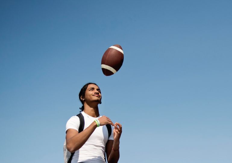 Une jeune personne lance un ballon de football en l'air