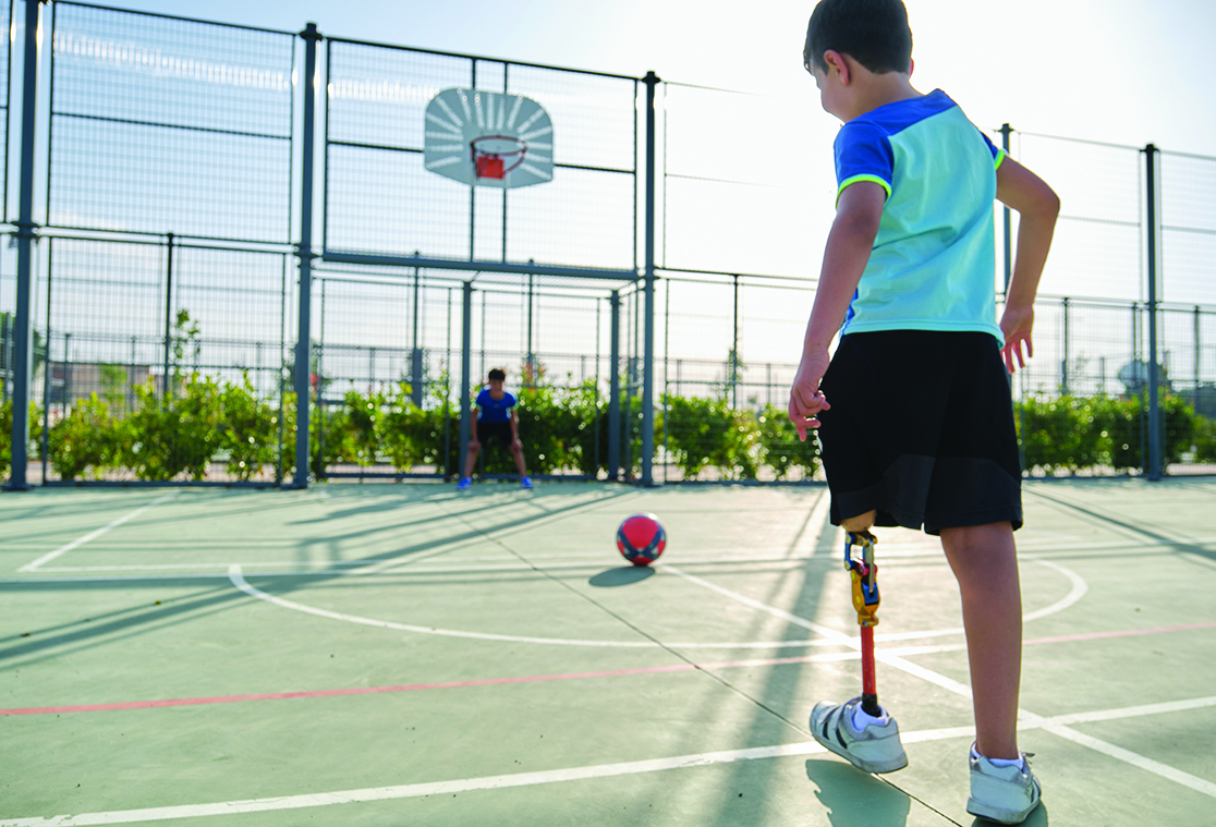 Jeune avec une prothèse de jambe qui joue avec un ballon