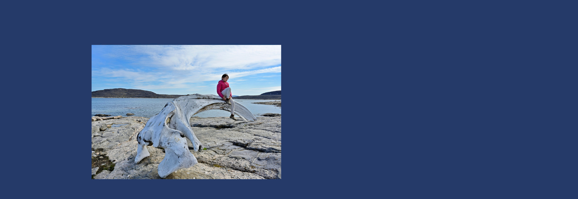 Un·e jeune Inuk perché·e sur un os de baleine, au bord de l’Arctique, sur l’île de Baffin.