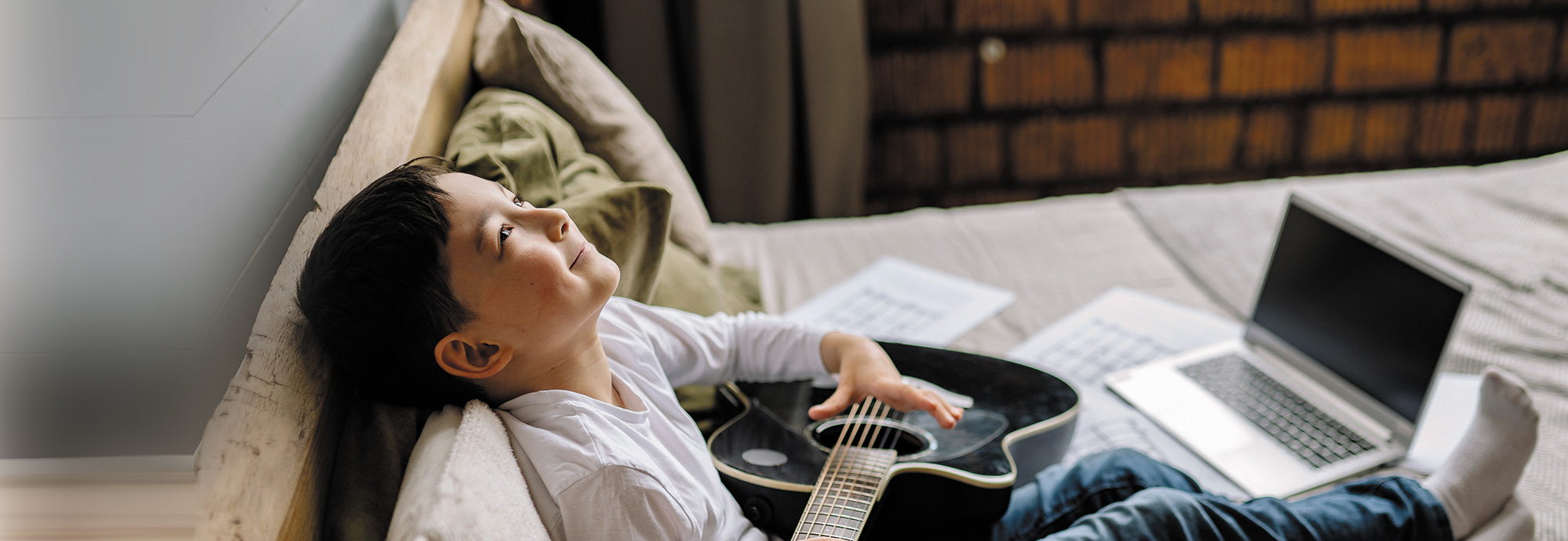 Un•e jeune tenant une guitare et fixant le plafond