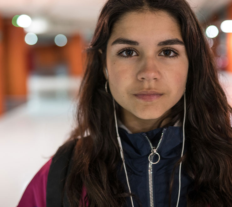 teen on a jacket and with headphones standing in the hallway