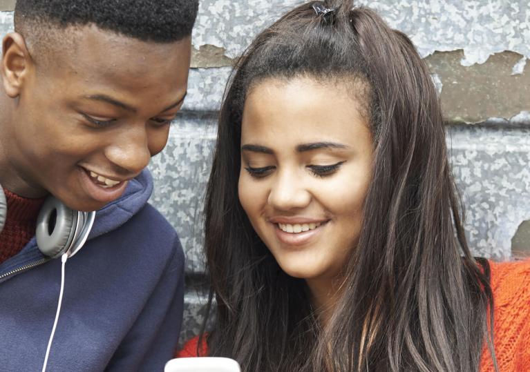 adolescents regardant un smartphone et souriant