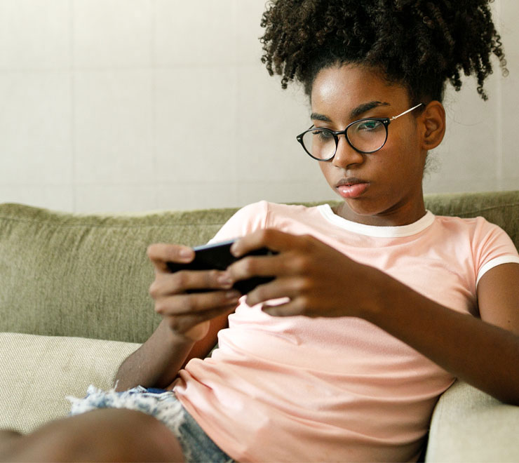teen sitting in a couch and using her phone