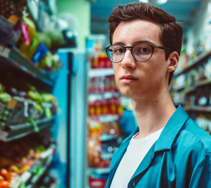 Un adolescent dans une épicerie qui songe à vapoter