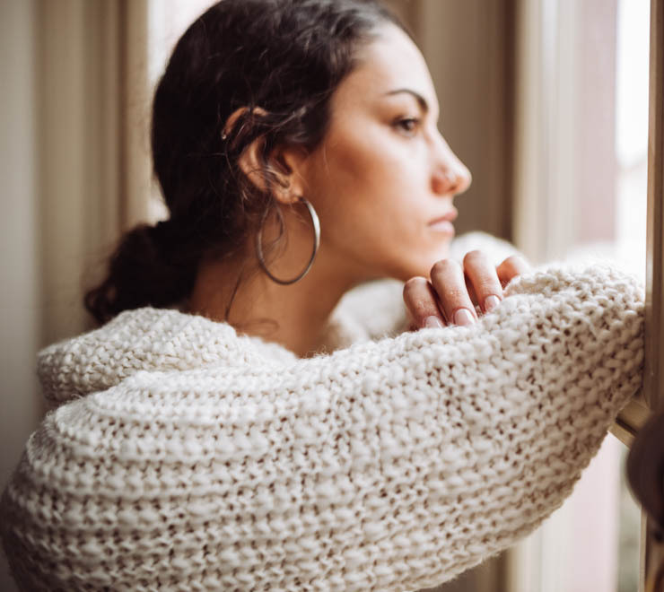 teen wearing a sweater and looking in a window